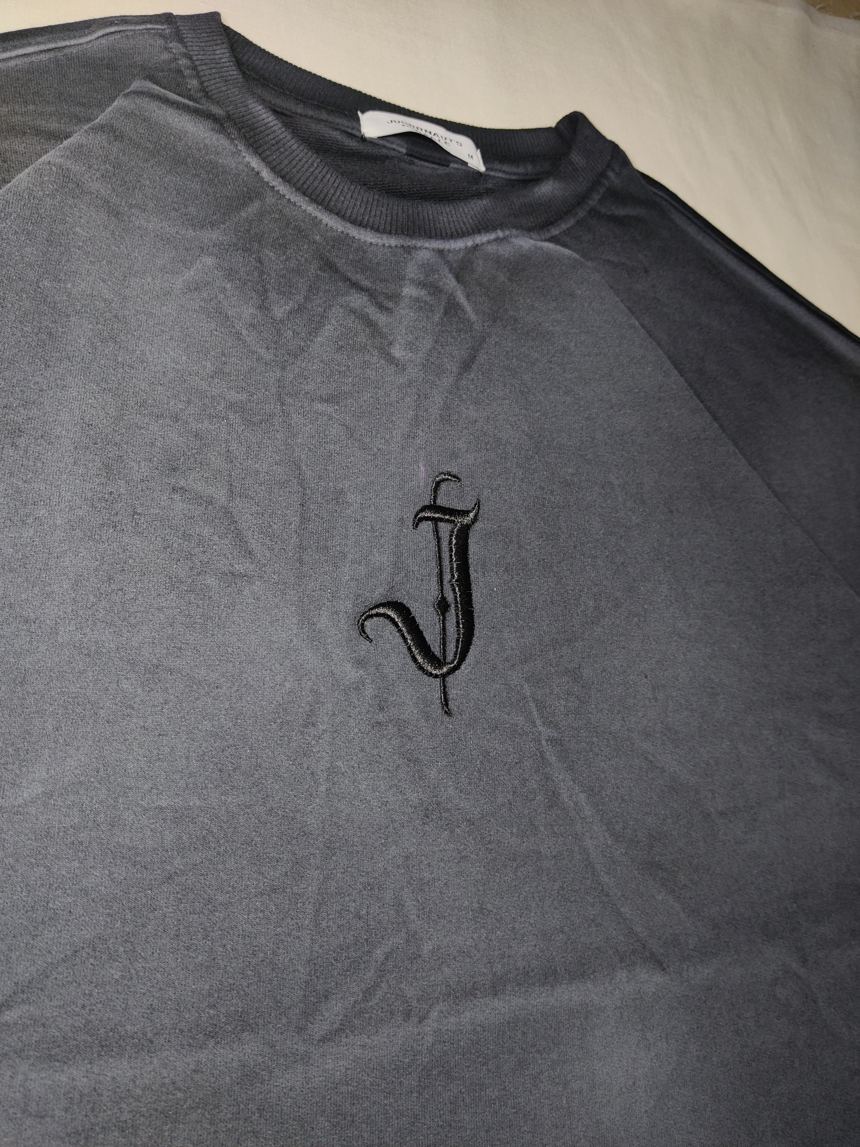 Gray tank top with a black embroidered design on a beige surface