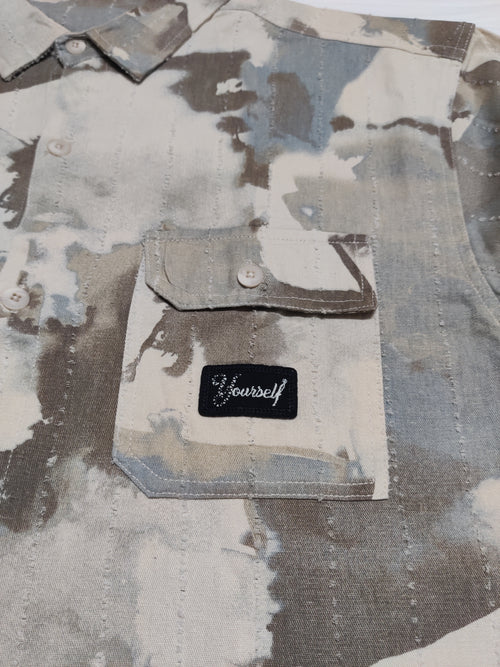 Camouflage-patterned shirt with a patch that says 'Be yourself' on a matching background