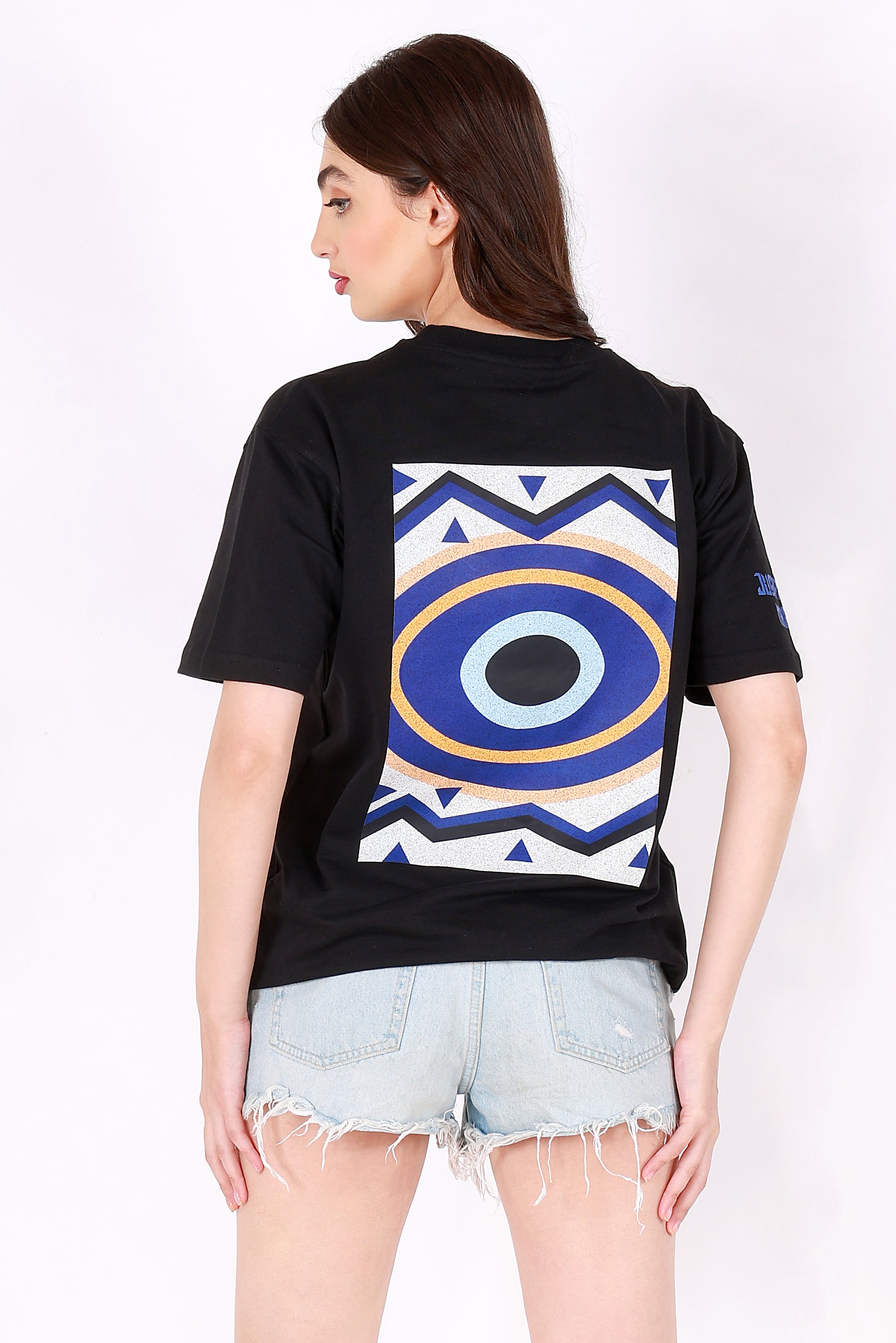 Person wearing a black t-shirt with a colorful geometric design on the back, standing against a white background.