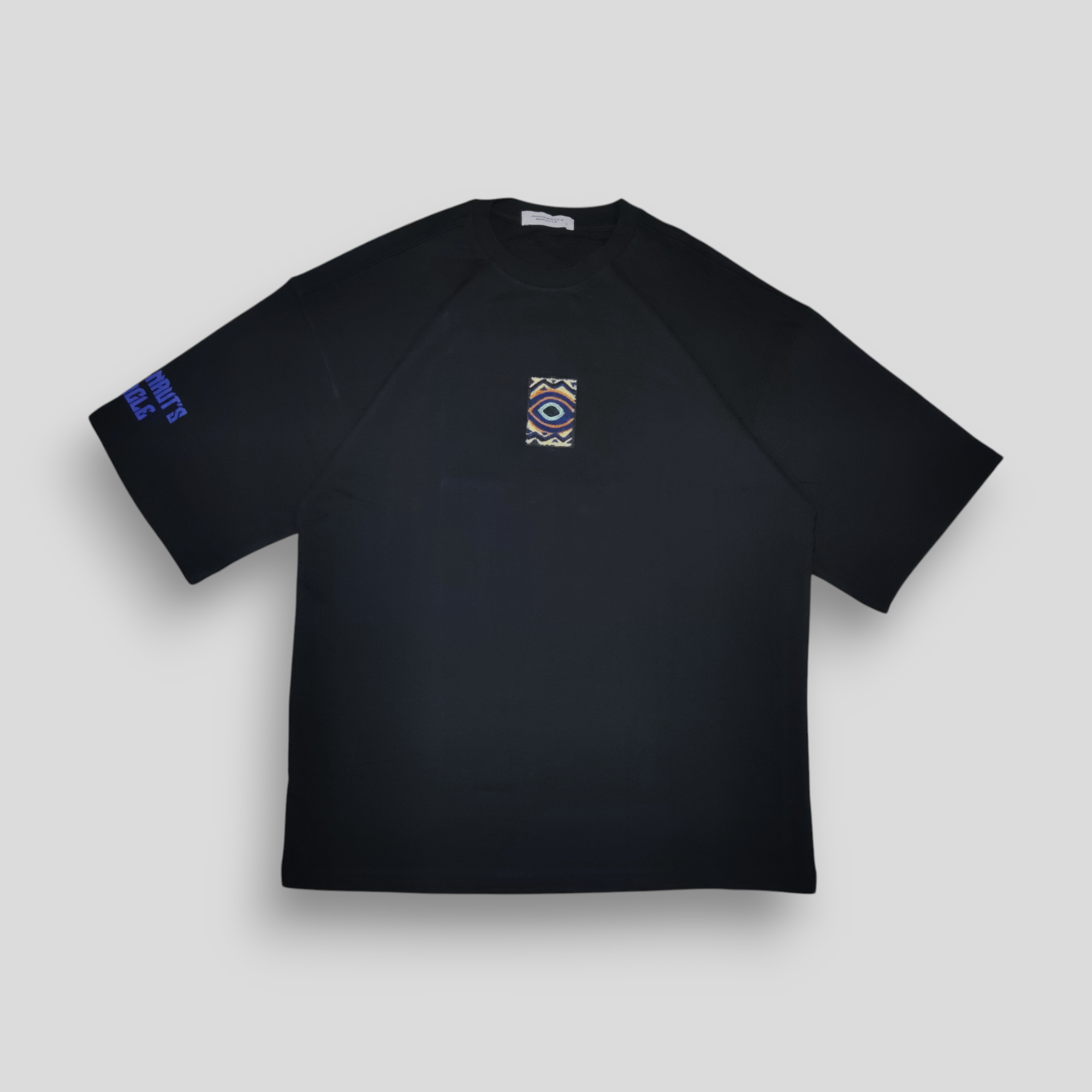 Black t-shirt with a chenille-embroidered patch on the front and a DTF-printed abstract graphic on the back, featuring a deep blue Jugrrnaut logo on the right sleeve.