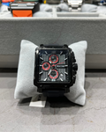 Black and red watch on a gray cushion with a blurred background