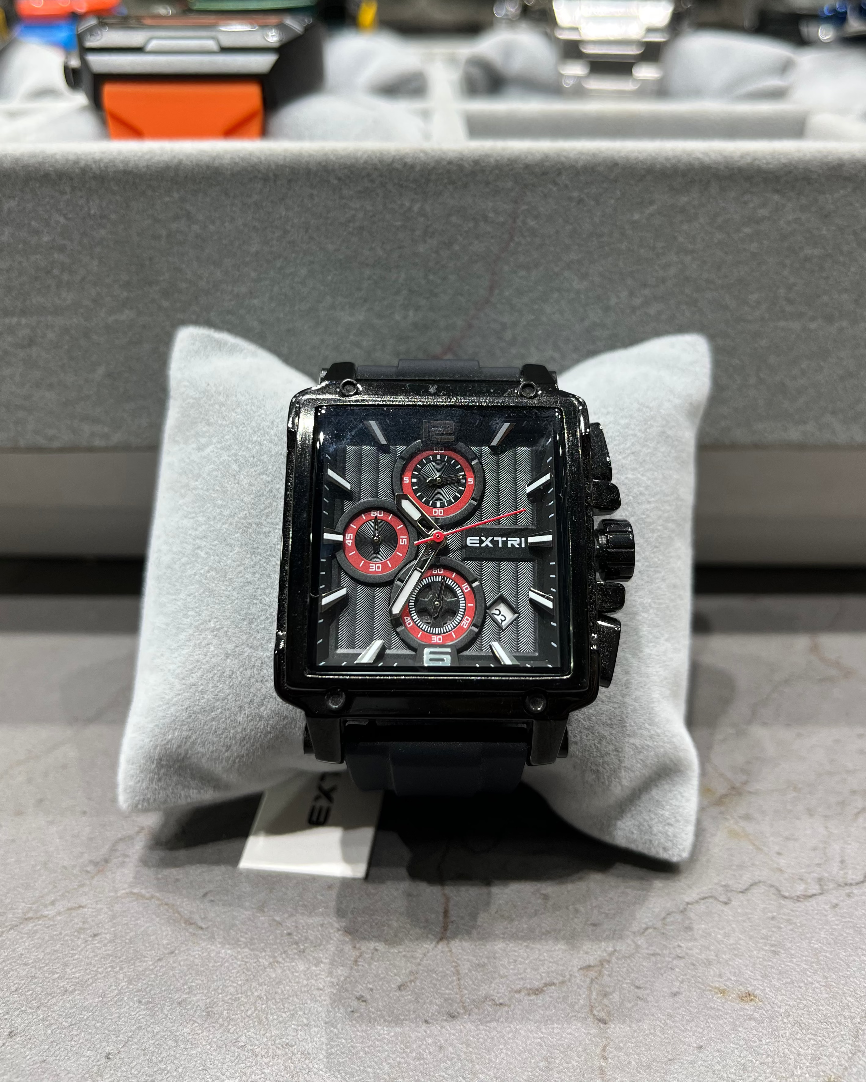 Black and red watch on a gray cushion with a blurred background