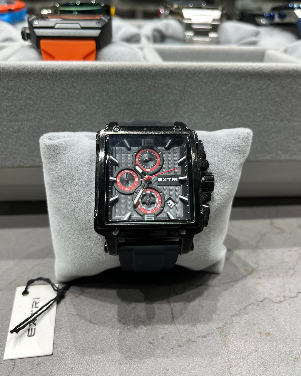 Black and red watch on a gray cushion with a blurred background