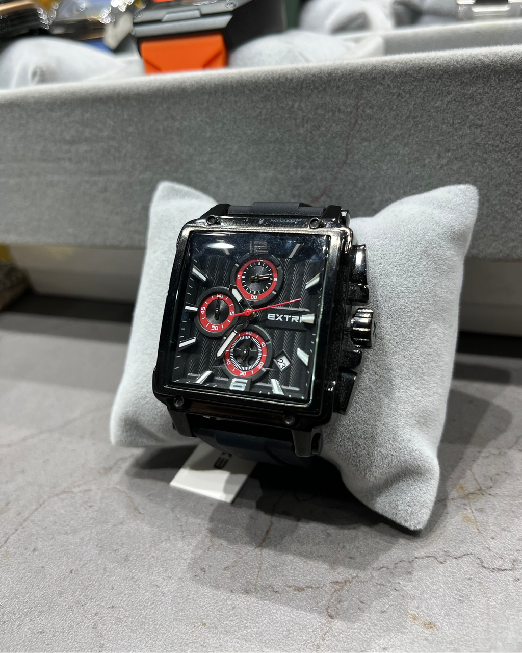 Black and red watch on a gray cushion with a blurred background