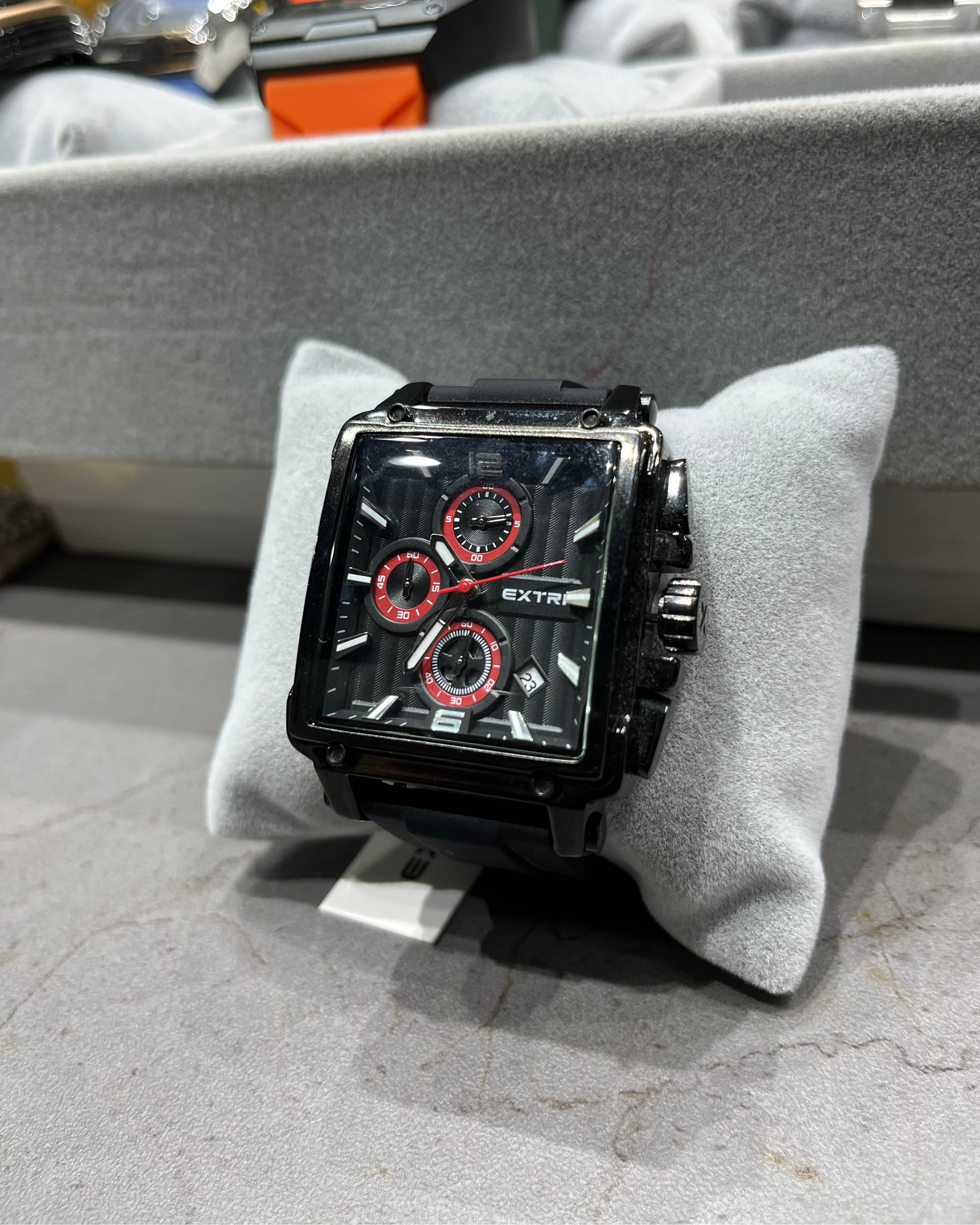 Black and red watch on a gray cushion with a blurred background