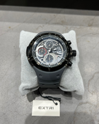 Black wristwatch on a gray surface with 'EXTRI' branding visible