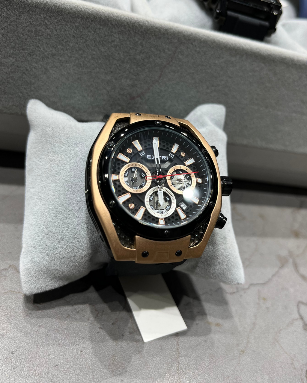 Luxury watch on a gray cushion with a blurred background