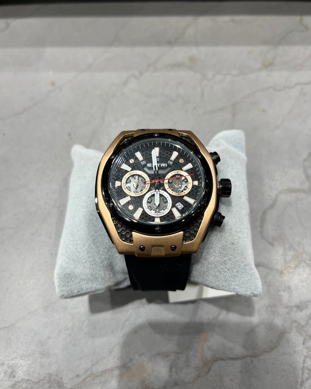 Luxury watch with black and gold design on a gray marble surface