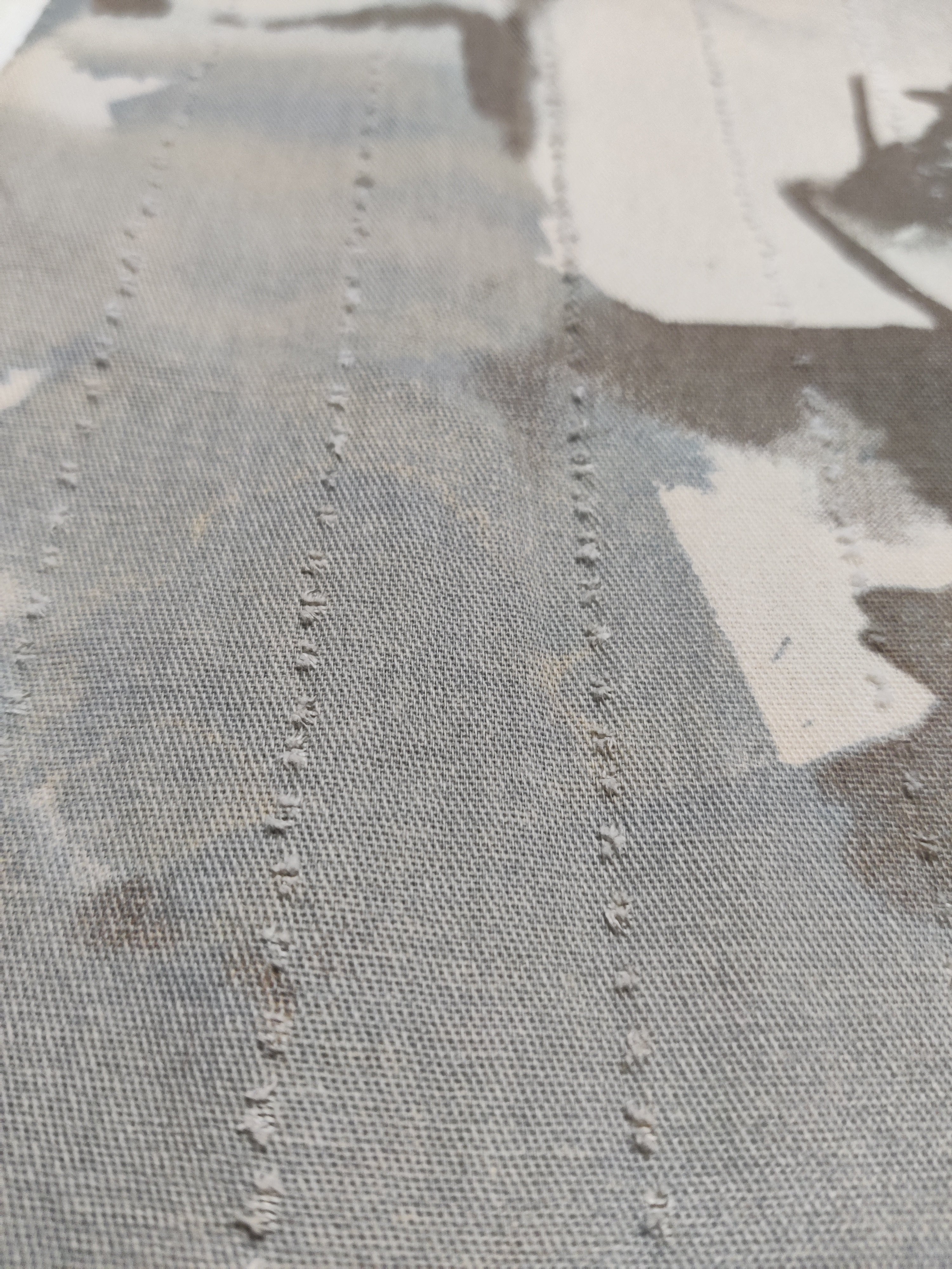 Close-up of a textured fabric surface with visible stitching details.
