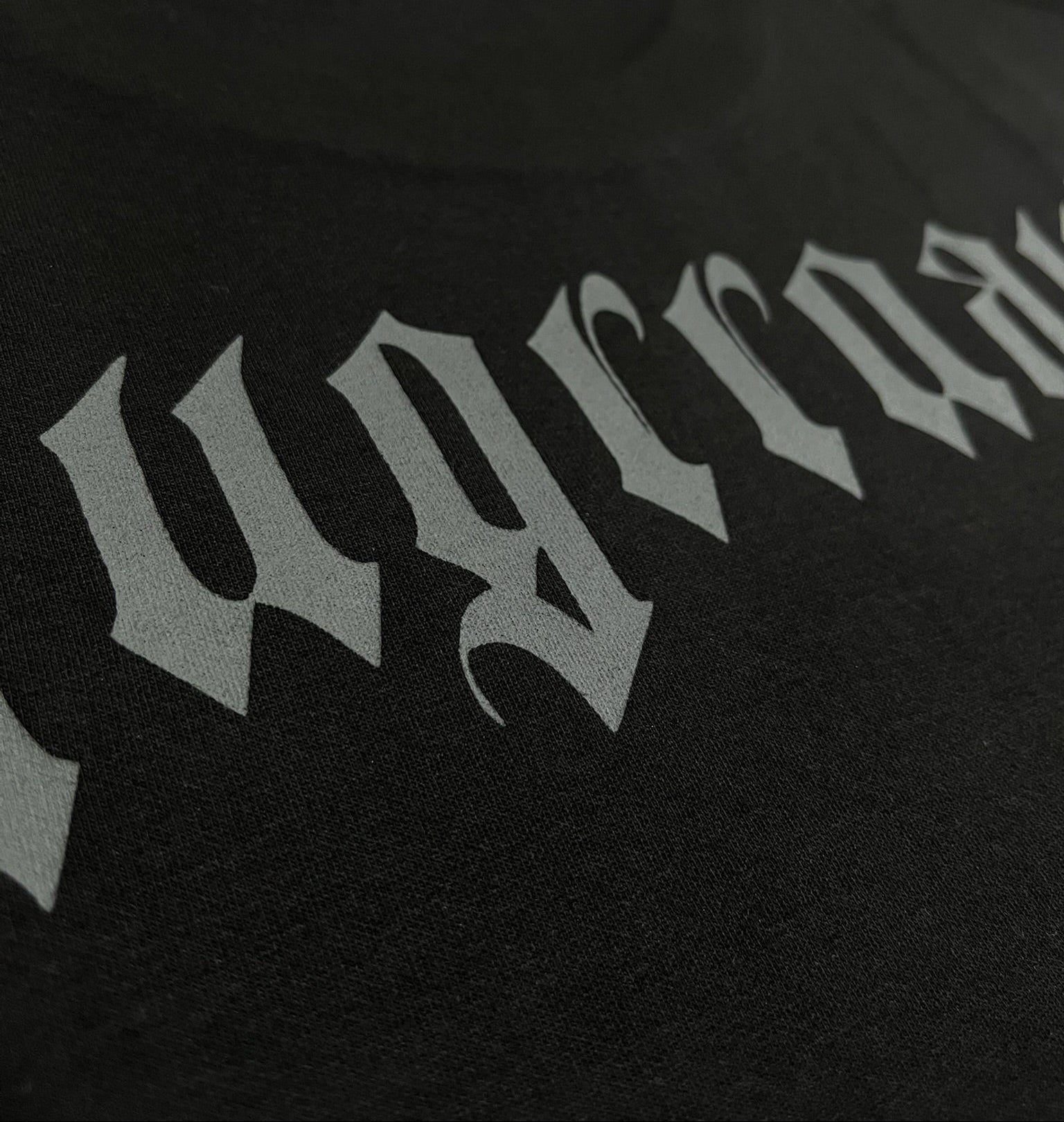 Black tshirt with grey text on a beige surface