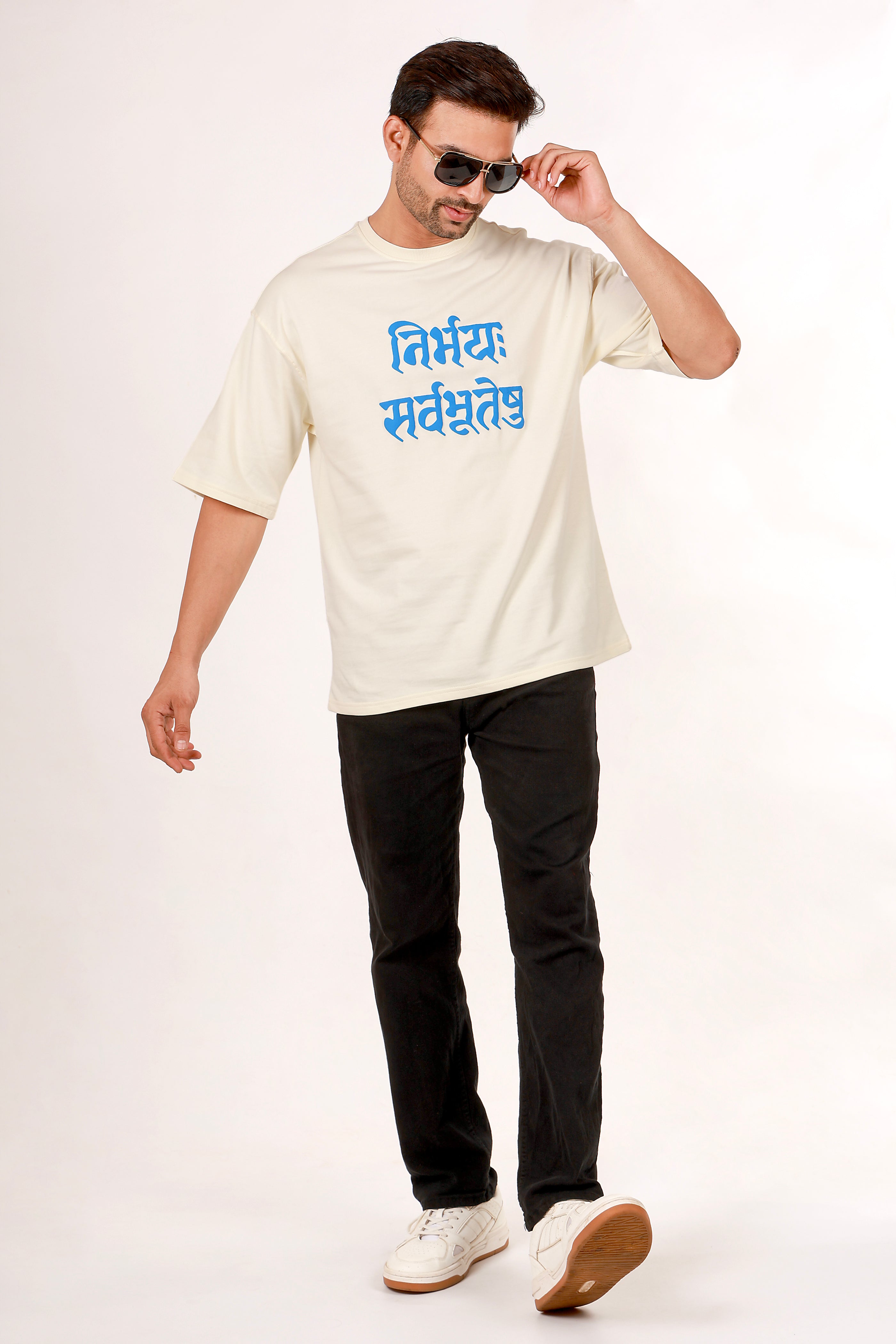 Man wearing a white t-shirt with blue sanskrit text and black pants on a white background