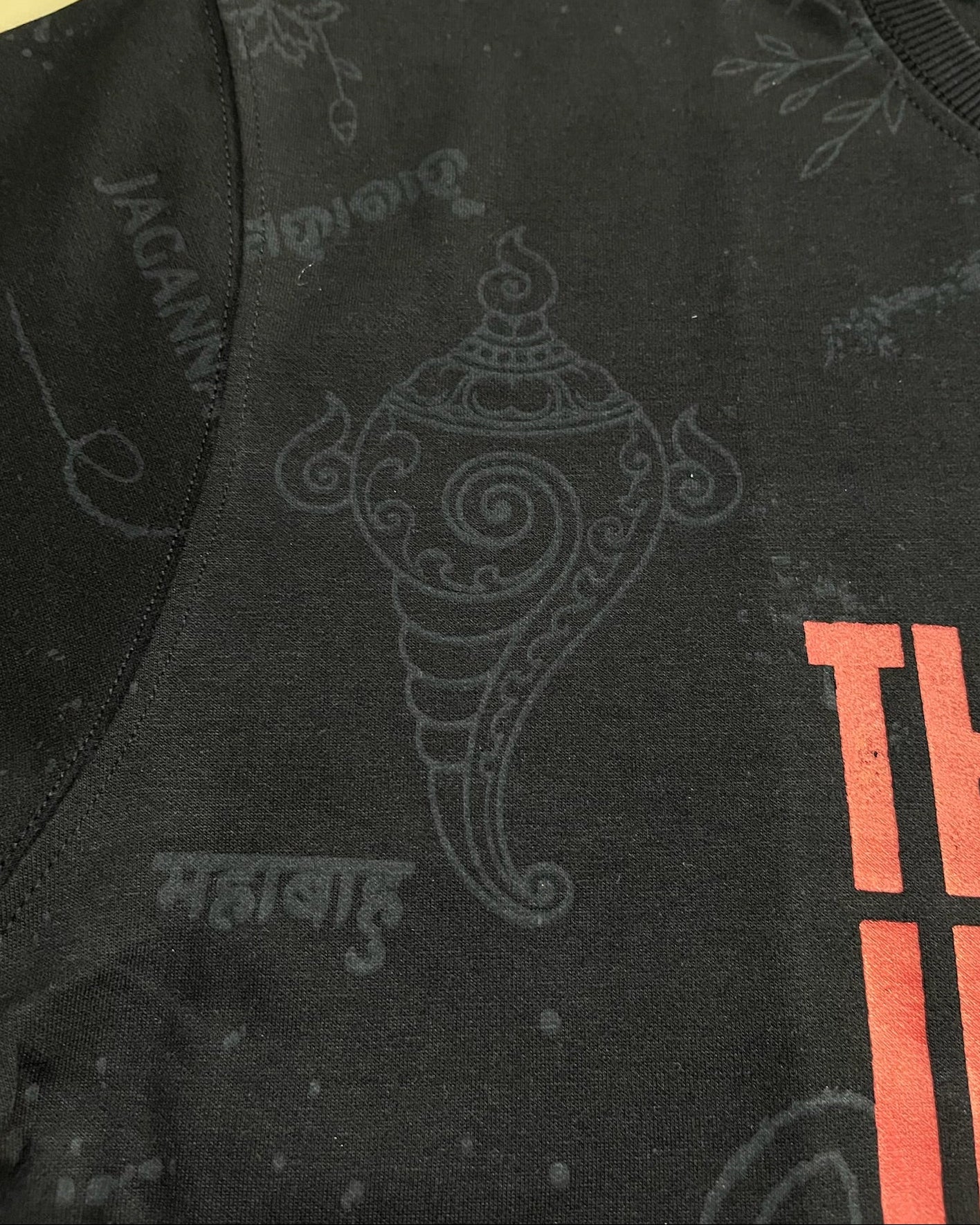 Black shirt with red text and intricate design on a yellow background