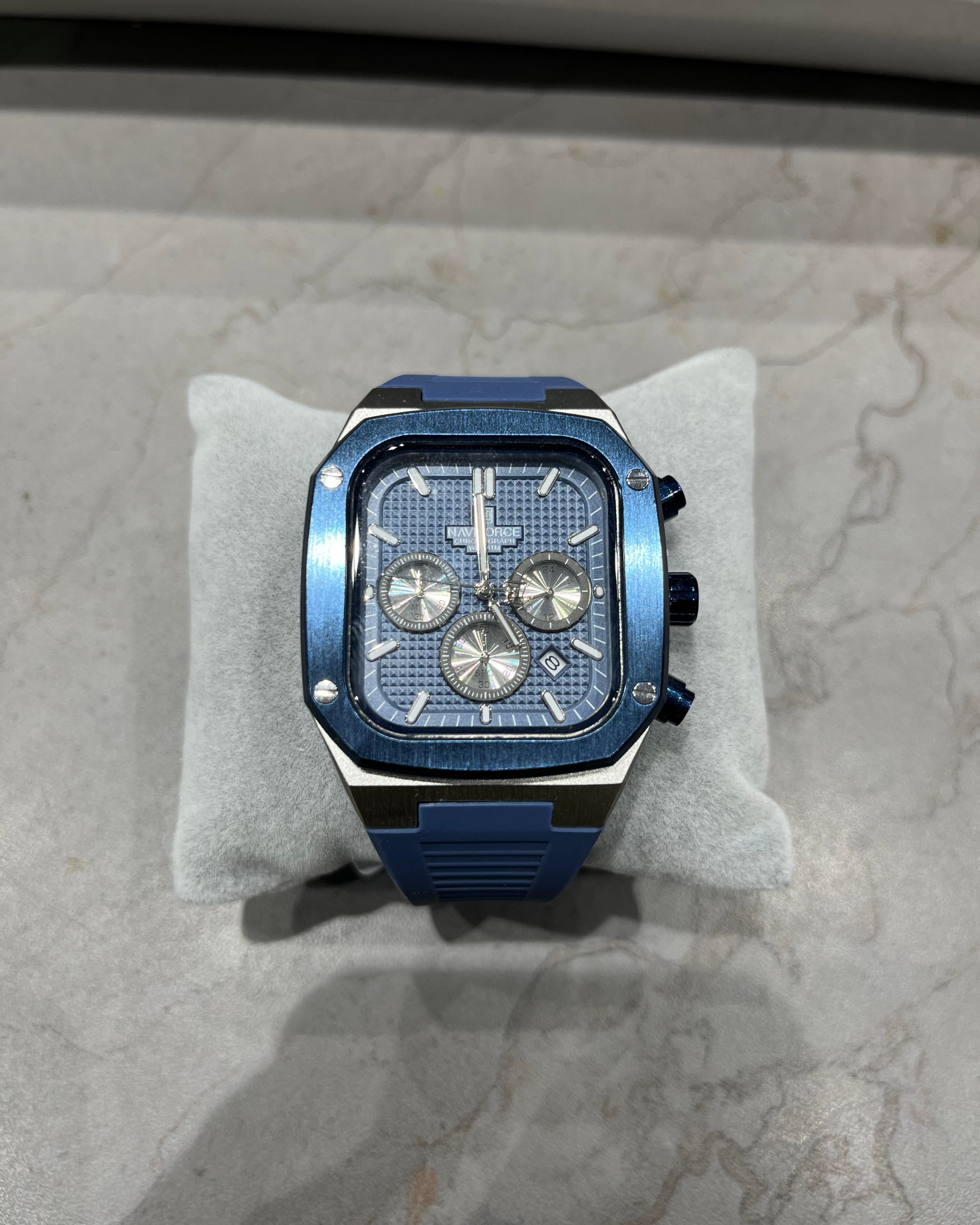 Blue watch on a gray cushion with a marble background