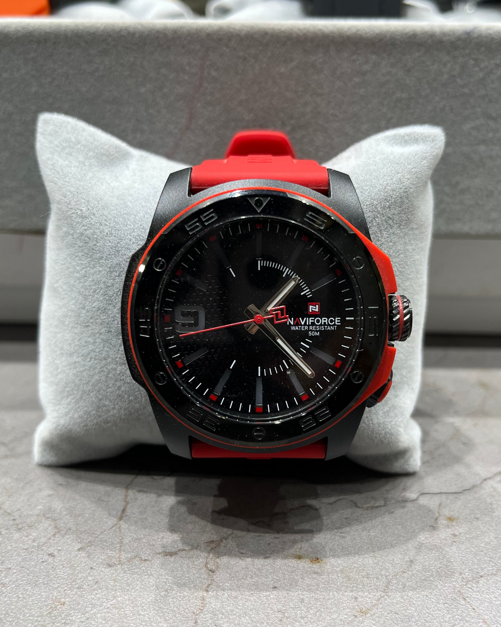Black and red watch on a gray cushion with a blurred background