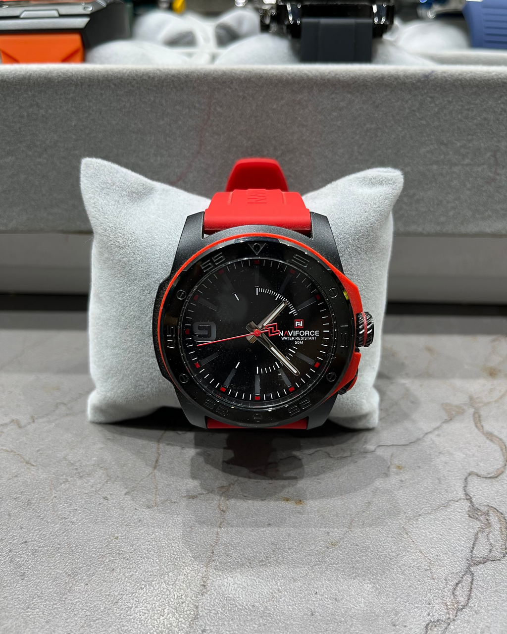 Black and red watch on a gray cushion with a blurred background