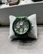 Green wristwatch on a gray cushion with a blurred background