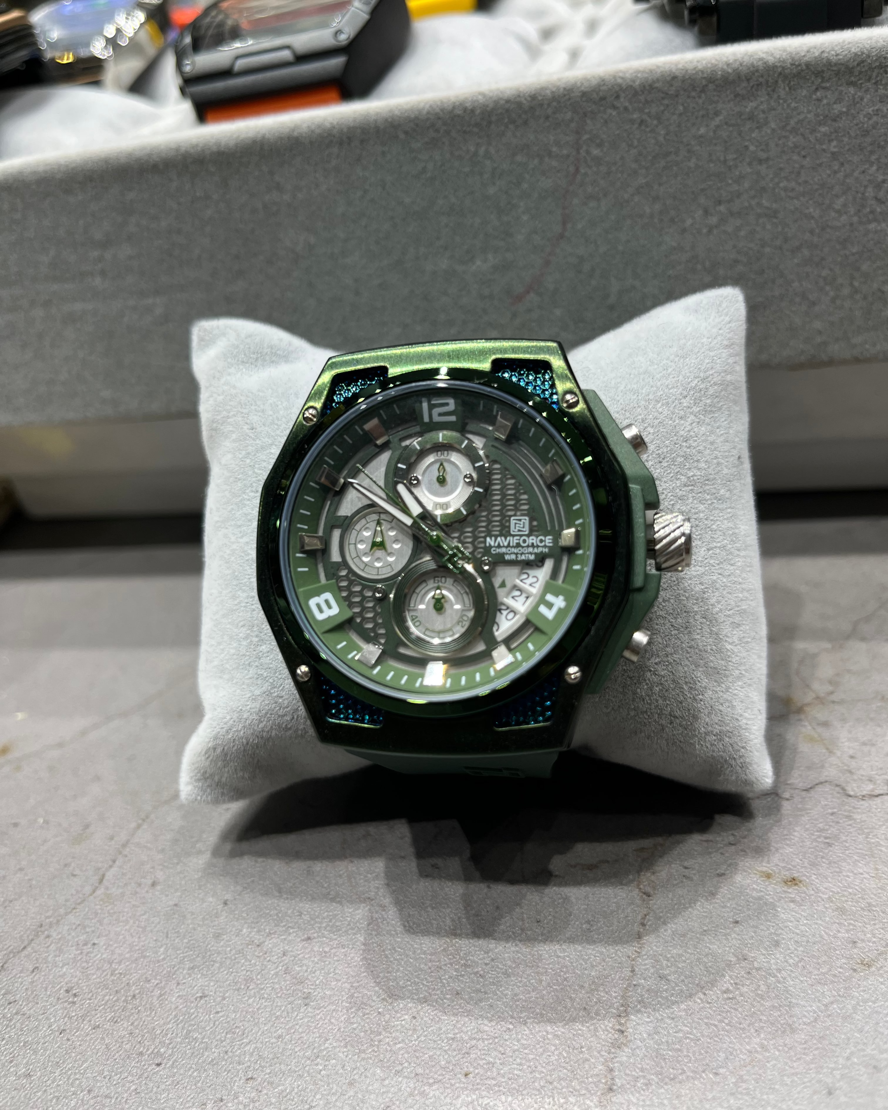 Green wristwatch on a gray cushion with a blurred background