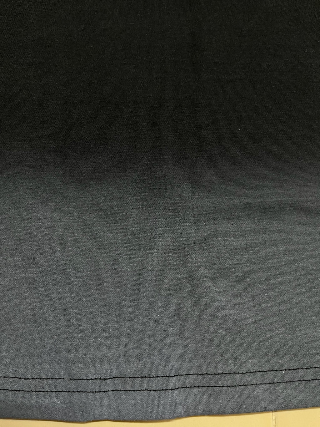 black fabric with a visible seam and grey spray on a beige floor surface