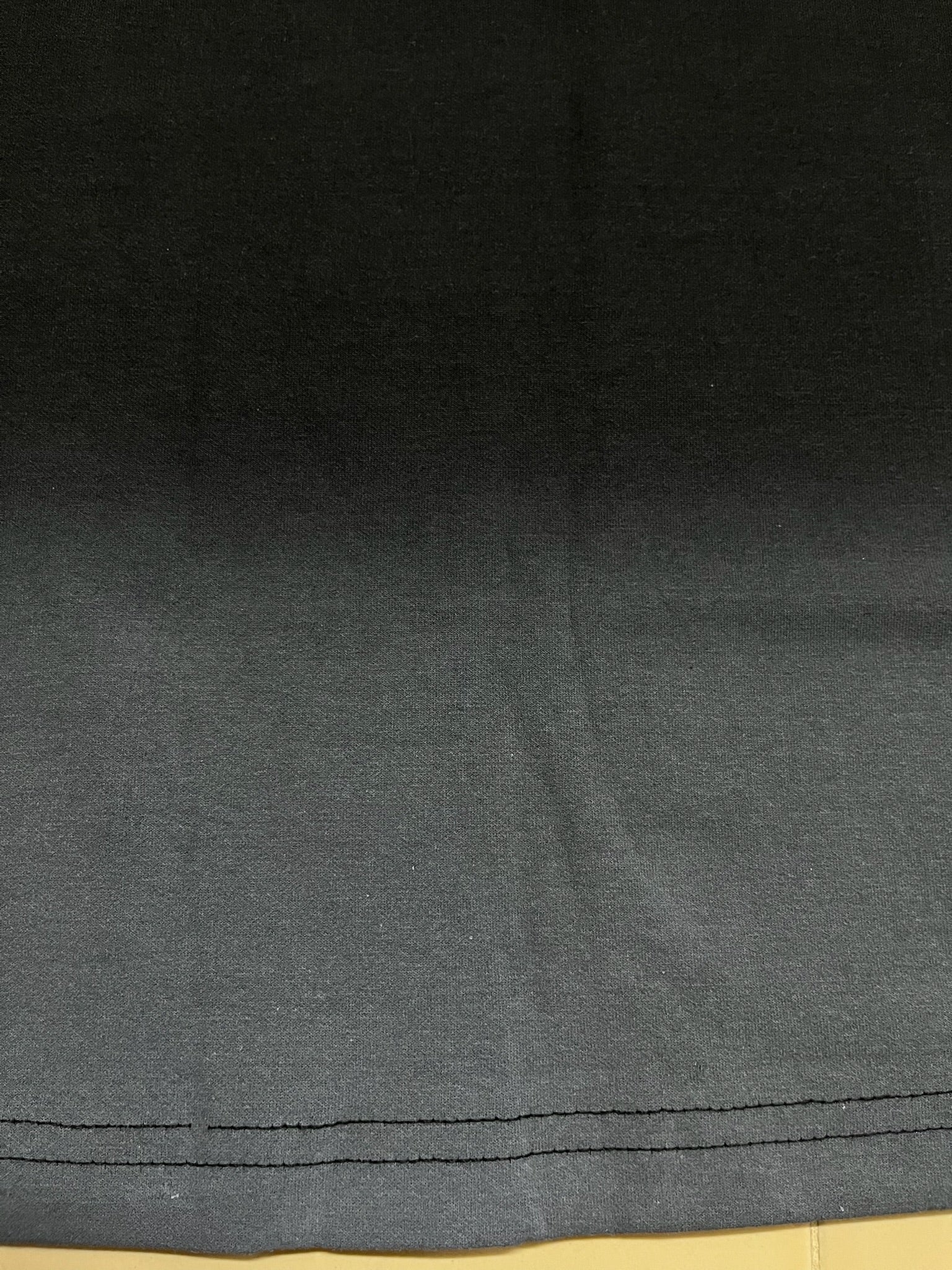 black fabric with a visible seam and grey spray on a beige floor surface