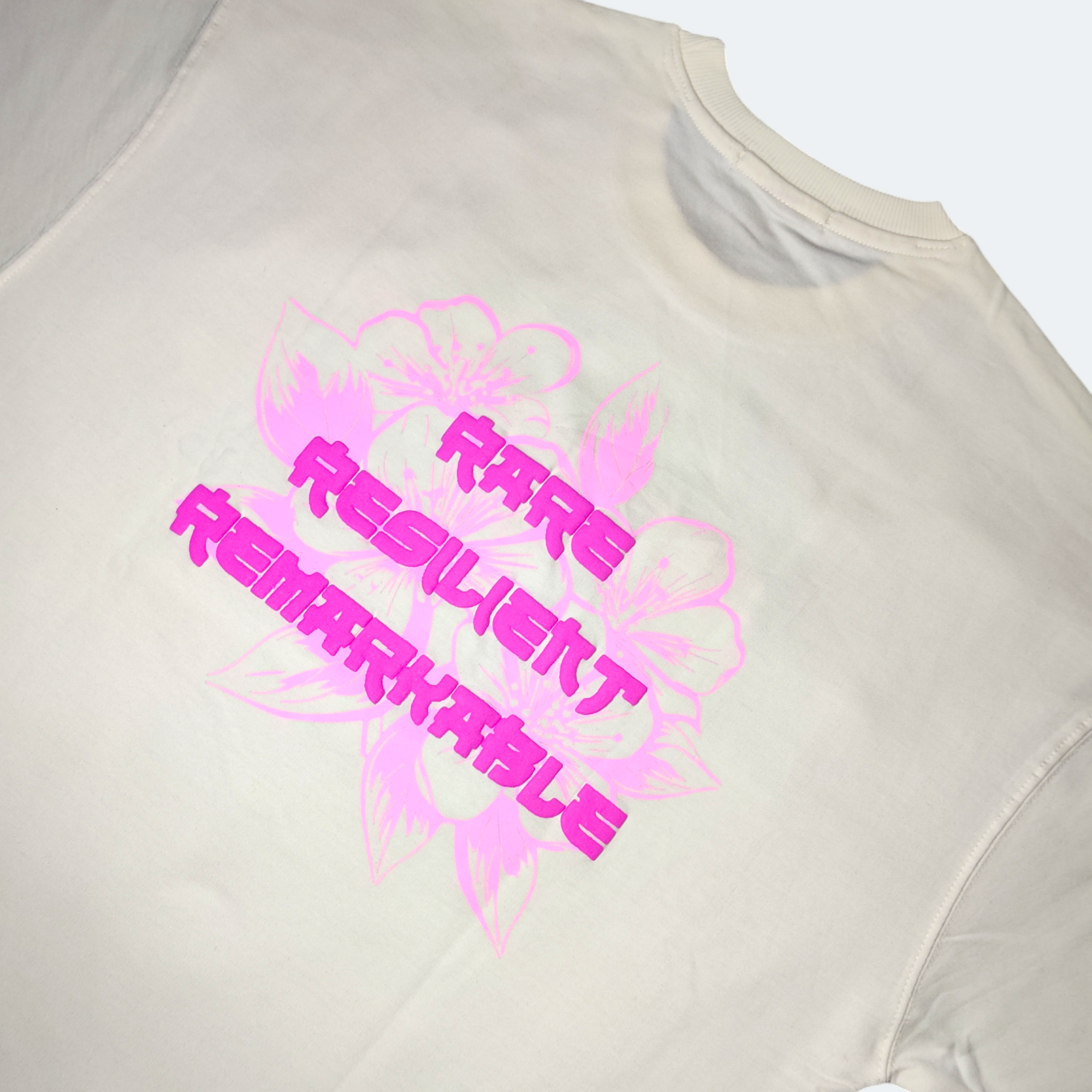 Beige t-shirt with pink and black motivational text on a white background