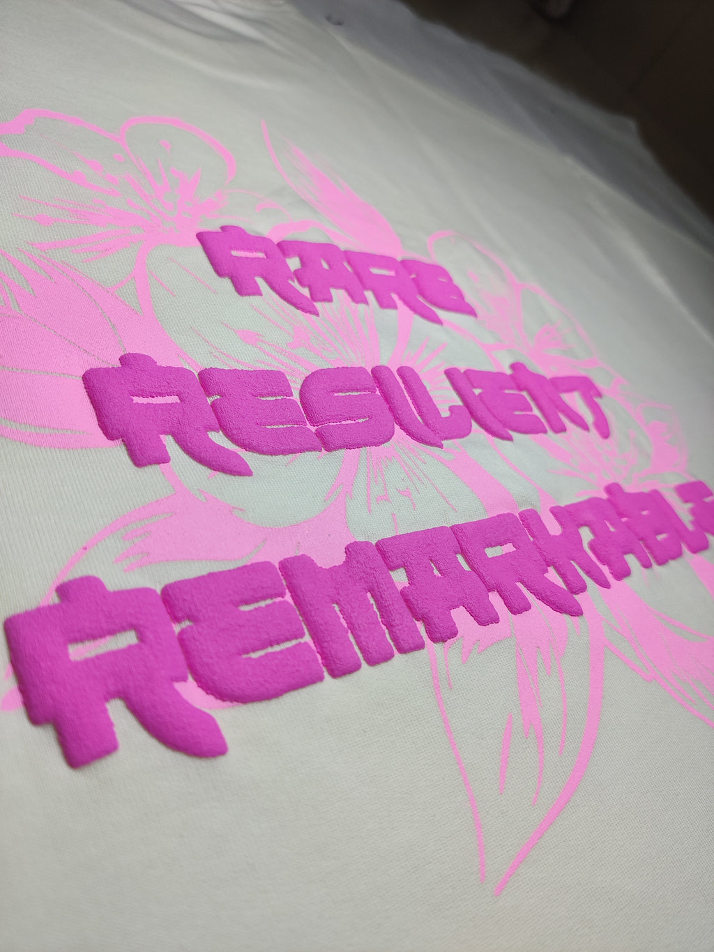 White shirt with pink text and graphics on a white background