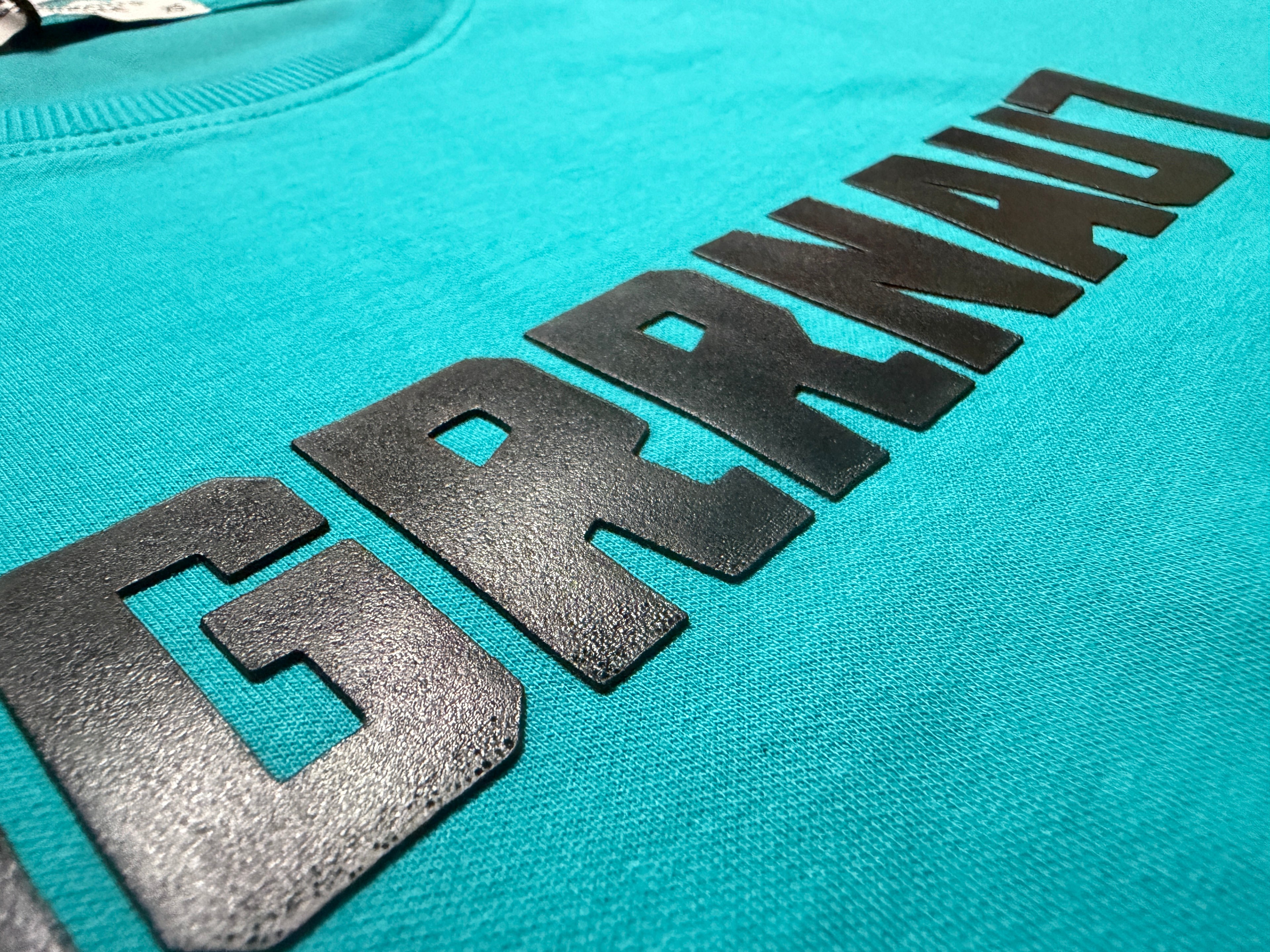 Teal tshirt with black logo on a turquoise background