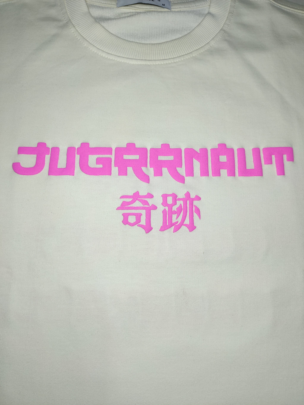 Beige oversized tshirt with pink text on a white background
