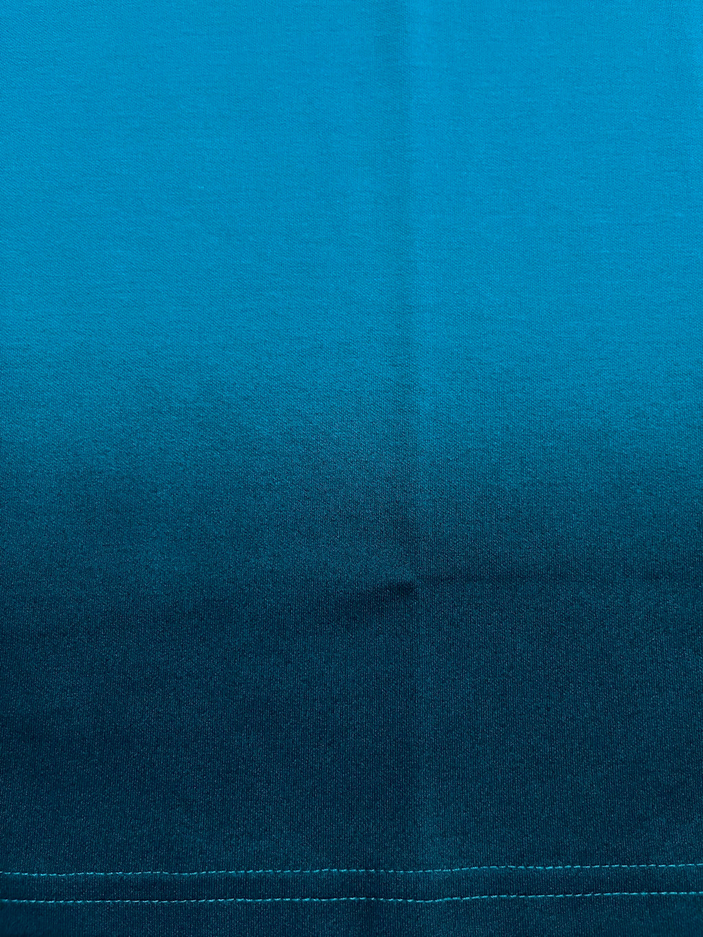 Close-up of blue fabric texture with black spray effect with visible seam line