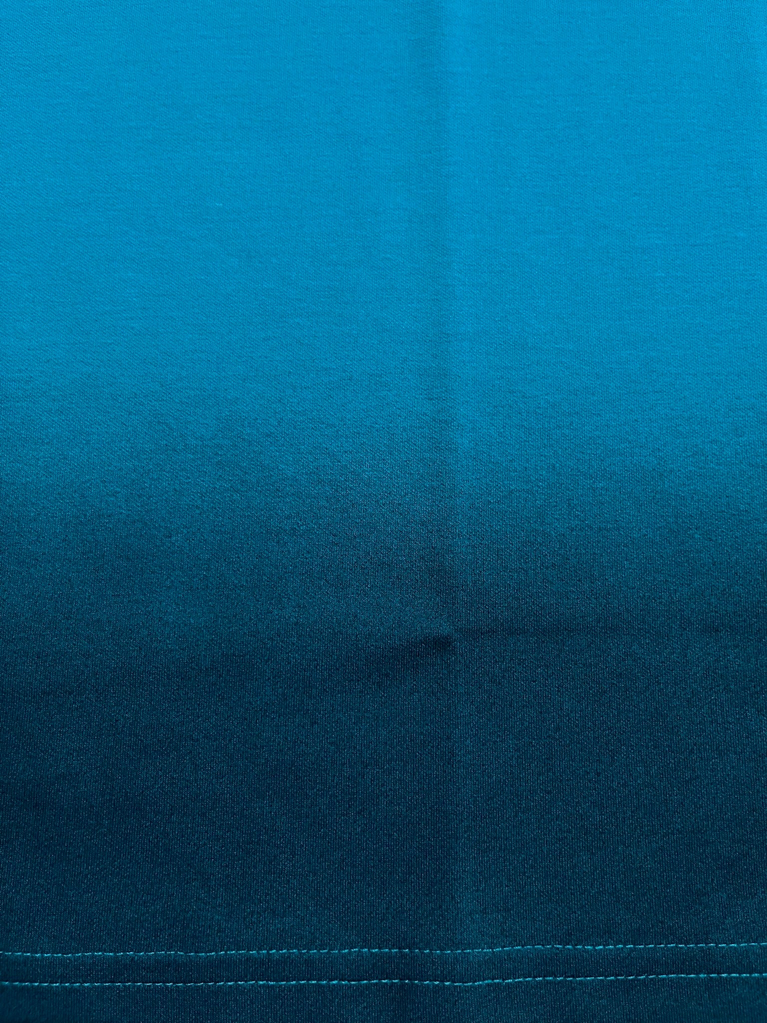 Close-up of blue fabric texture with black spray effect with visible seam line