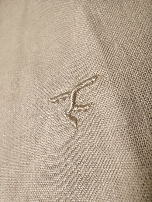Close-up of a beige fabric with a small embroidered logo.