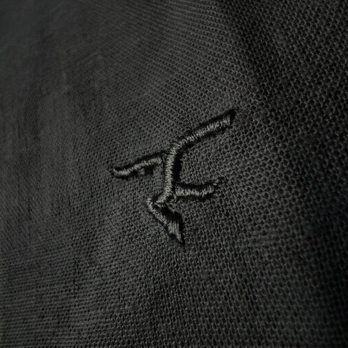 Close-up of a black embroidered logo on a dark fabric background