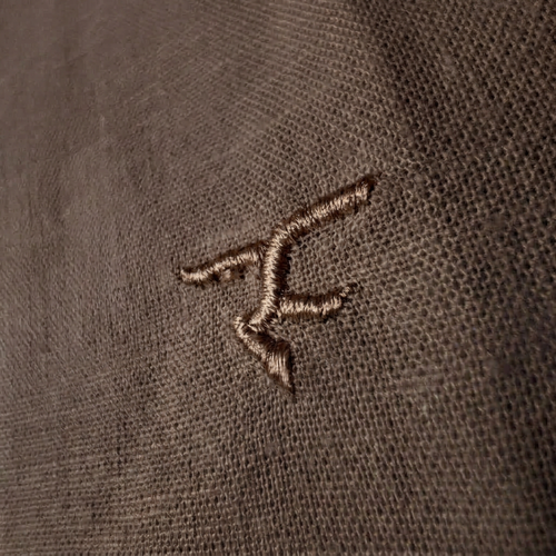 Close-up of a brown embroidered logo on a textured fabric background