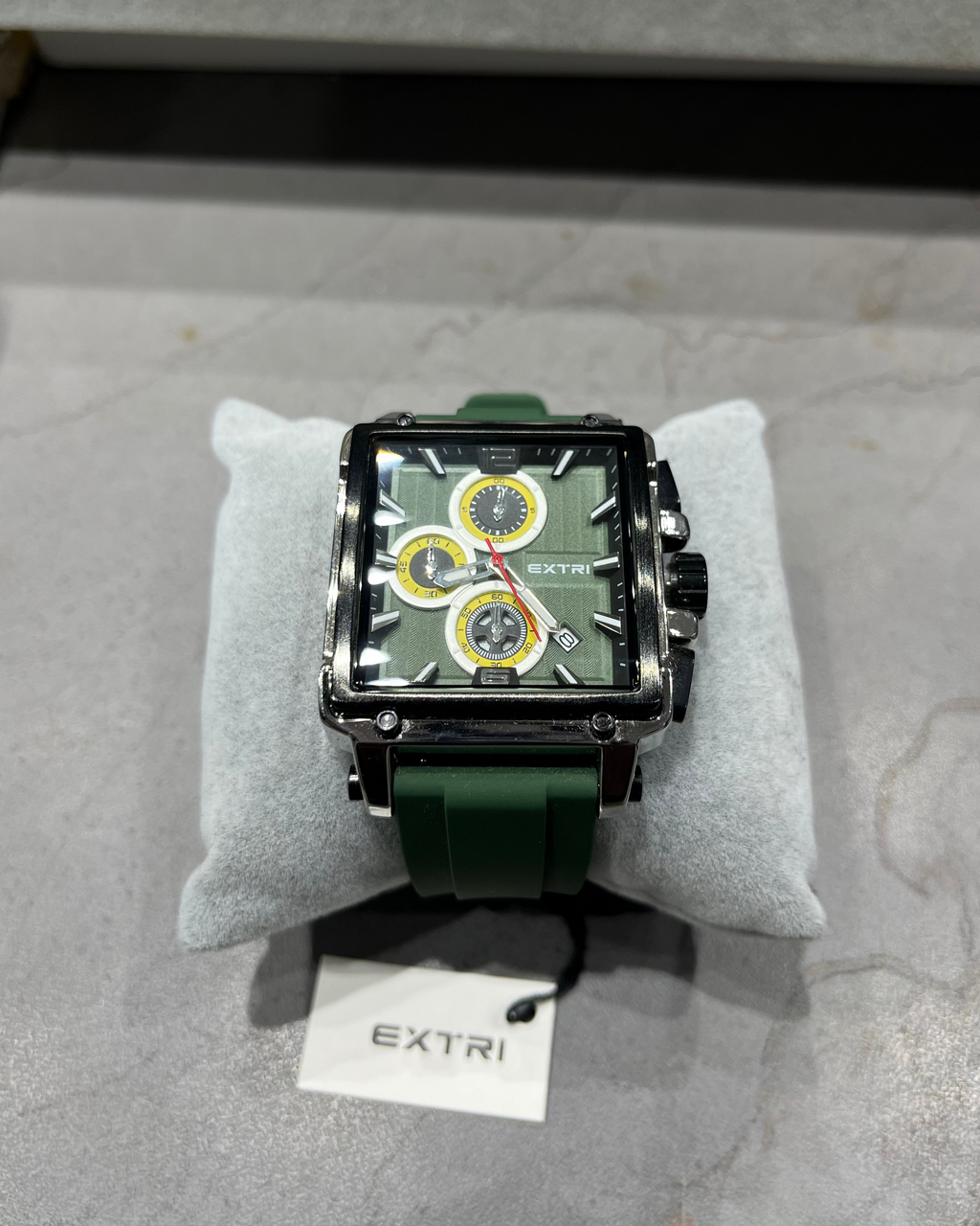 Green watch with detailed face on a gray surface, branded 'EXTRI'