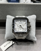 Luxury watch with 'Extri' branding on a gray cushion with a blurred background.