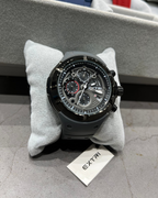 Black wristwatch on a gray cushion with 'EXTRI' branding, surrounded by other watches in the background.