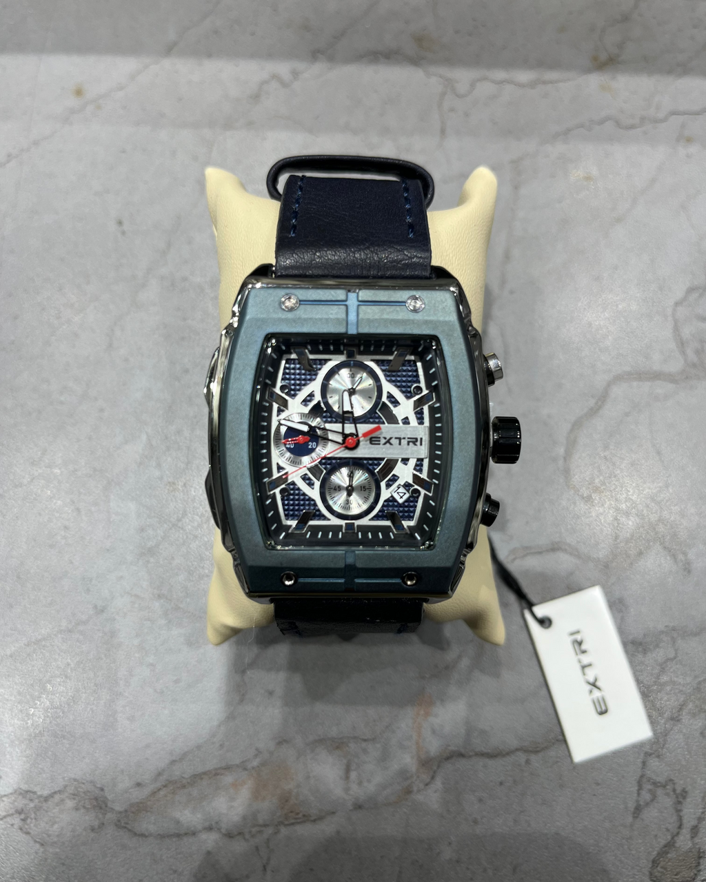 Luxury watch with a black strap on a gray surface, featuring the brand 'EXTRI'.