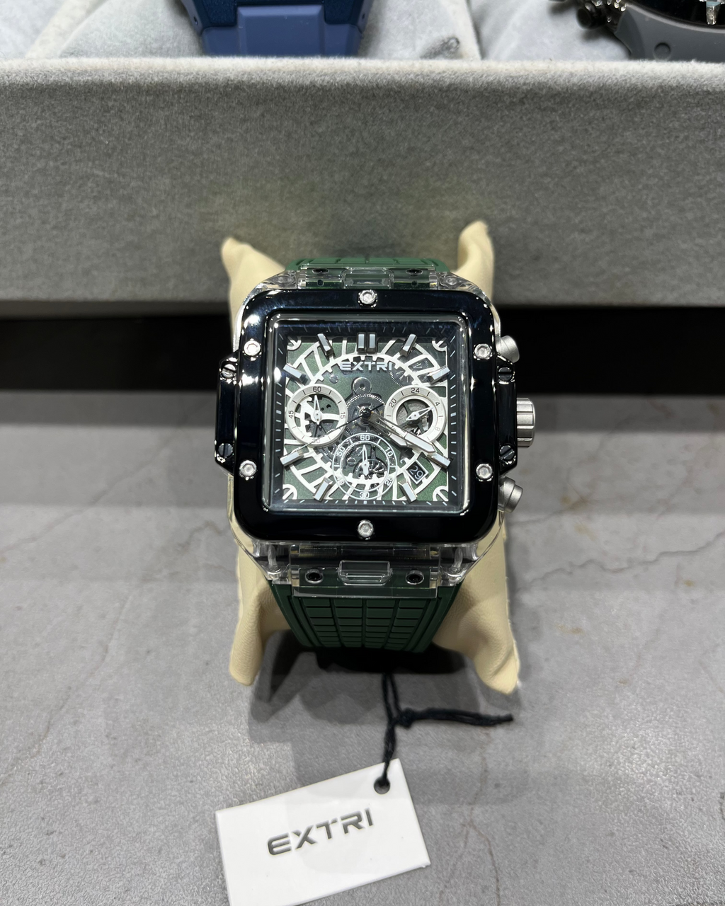 Luxury watch with intricate design on a gray surface, branded 'EXTRI'.
