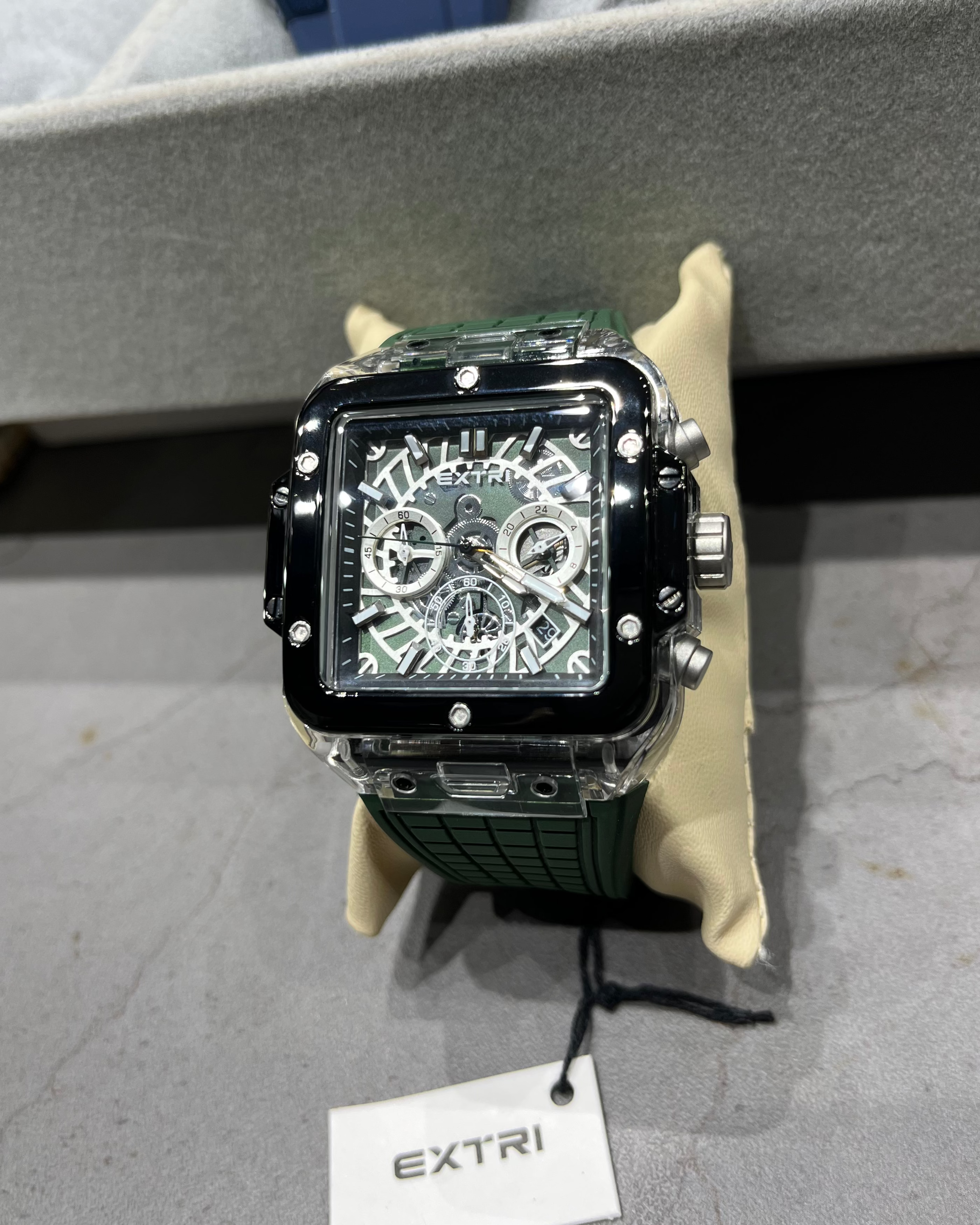 Luxury watch with intricate design on a gray surface, branded 'EXTRI'.