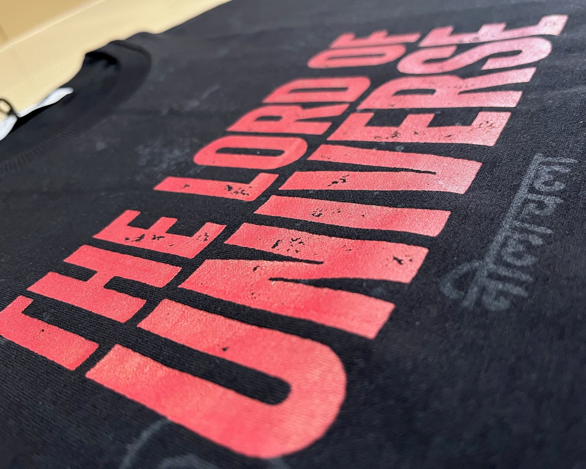 Black t-shirt with red and grey text on a plain background