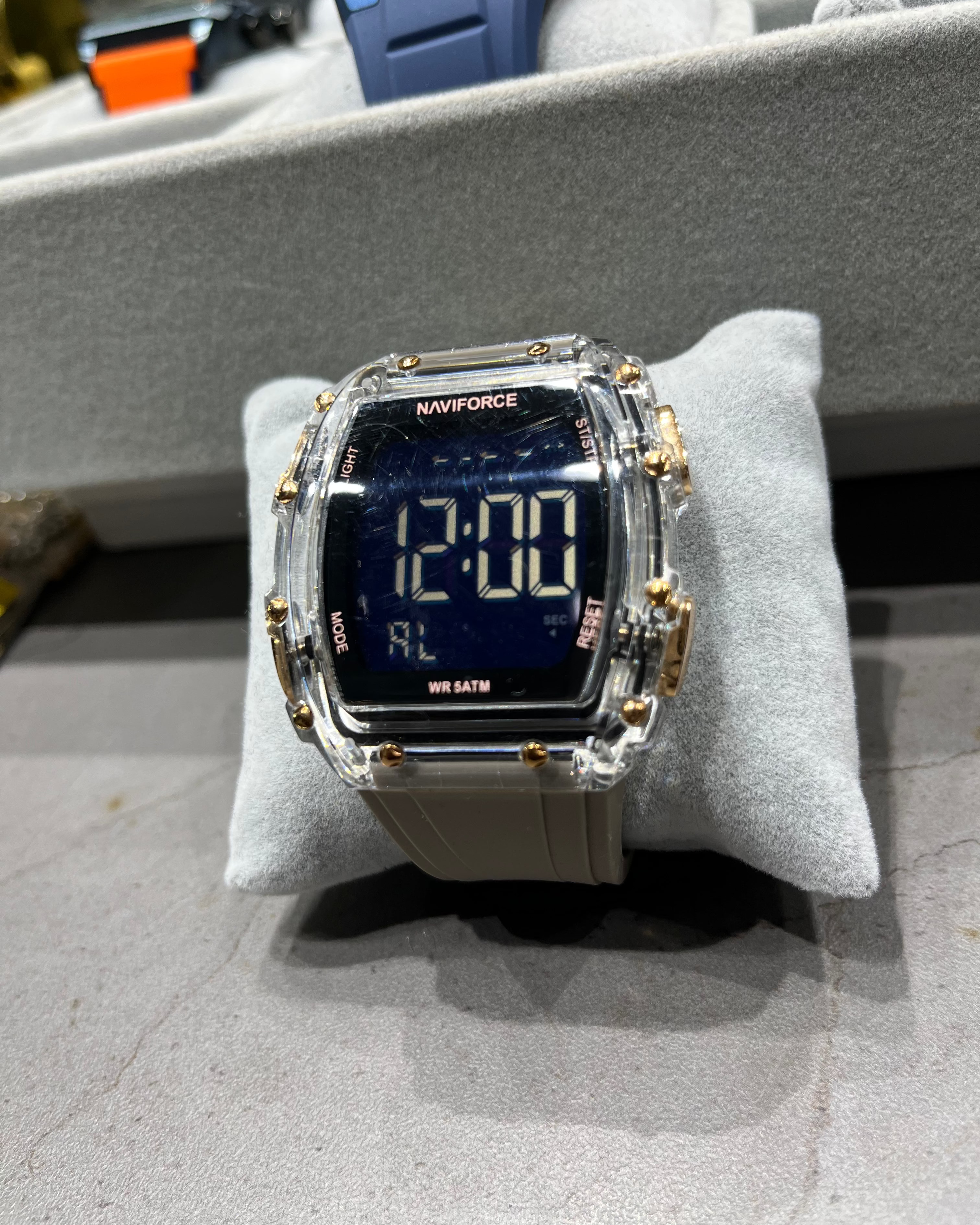 Digital watch with gold accents on a gray cushion, blurred background