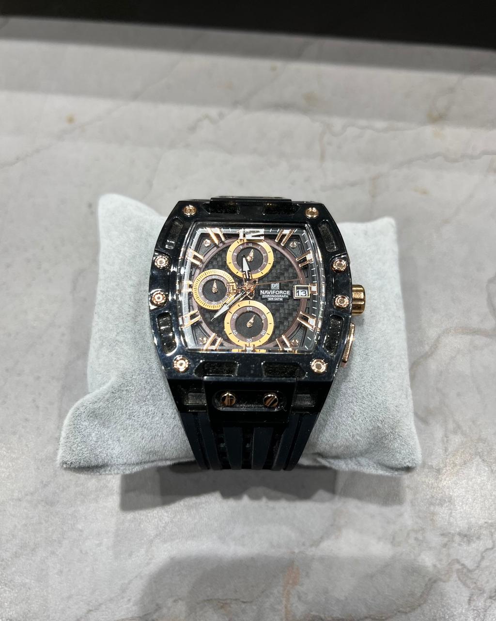 Luxury watch with black and gold design on a gray cushion