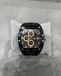 Luxury watch with black and gold design on a gray cushion against a marble background
