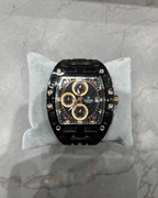 Luxury watch with black and gold design on a gray cushion against a marble background