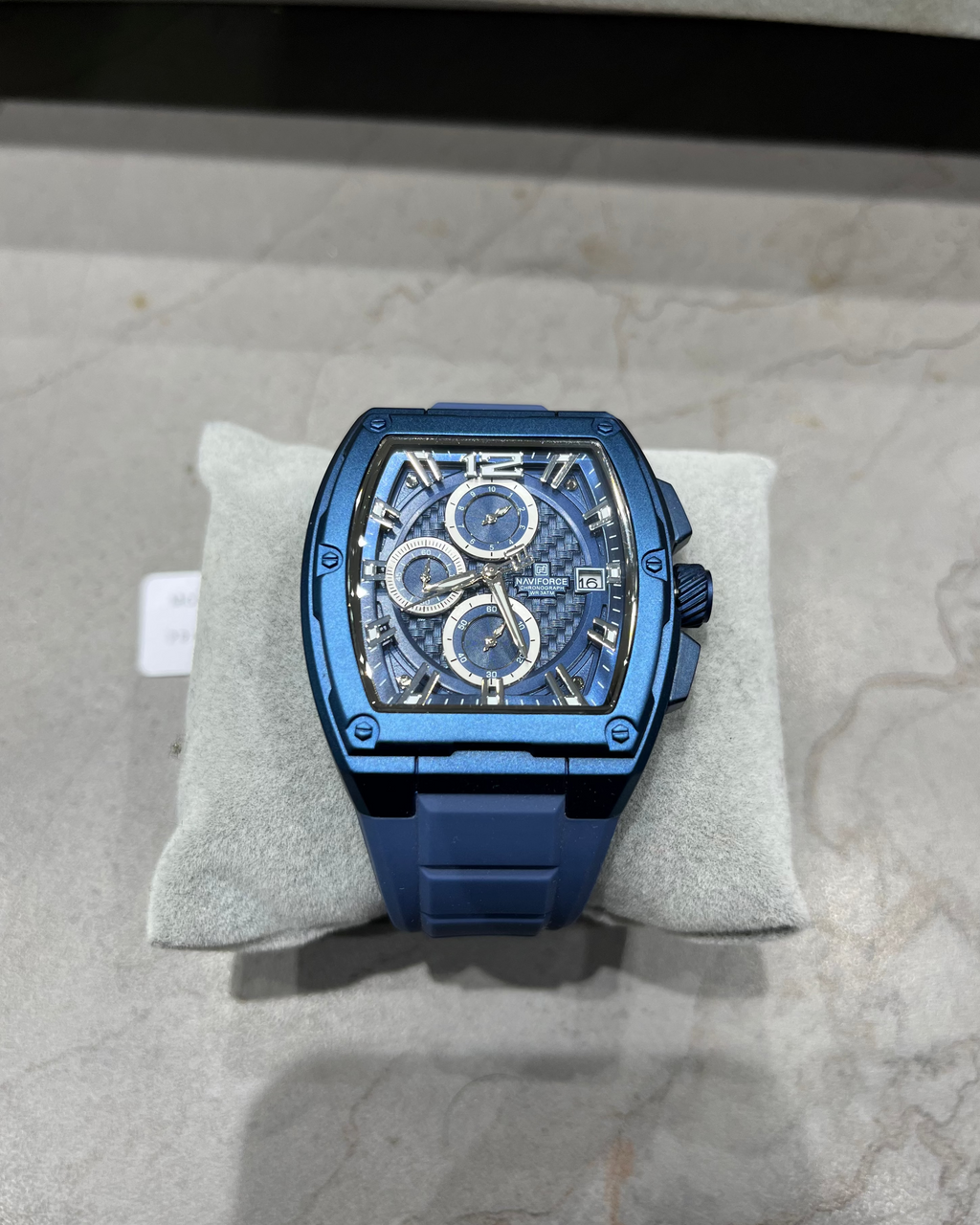 Blue watch on a gray cushion with a neutral background