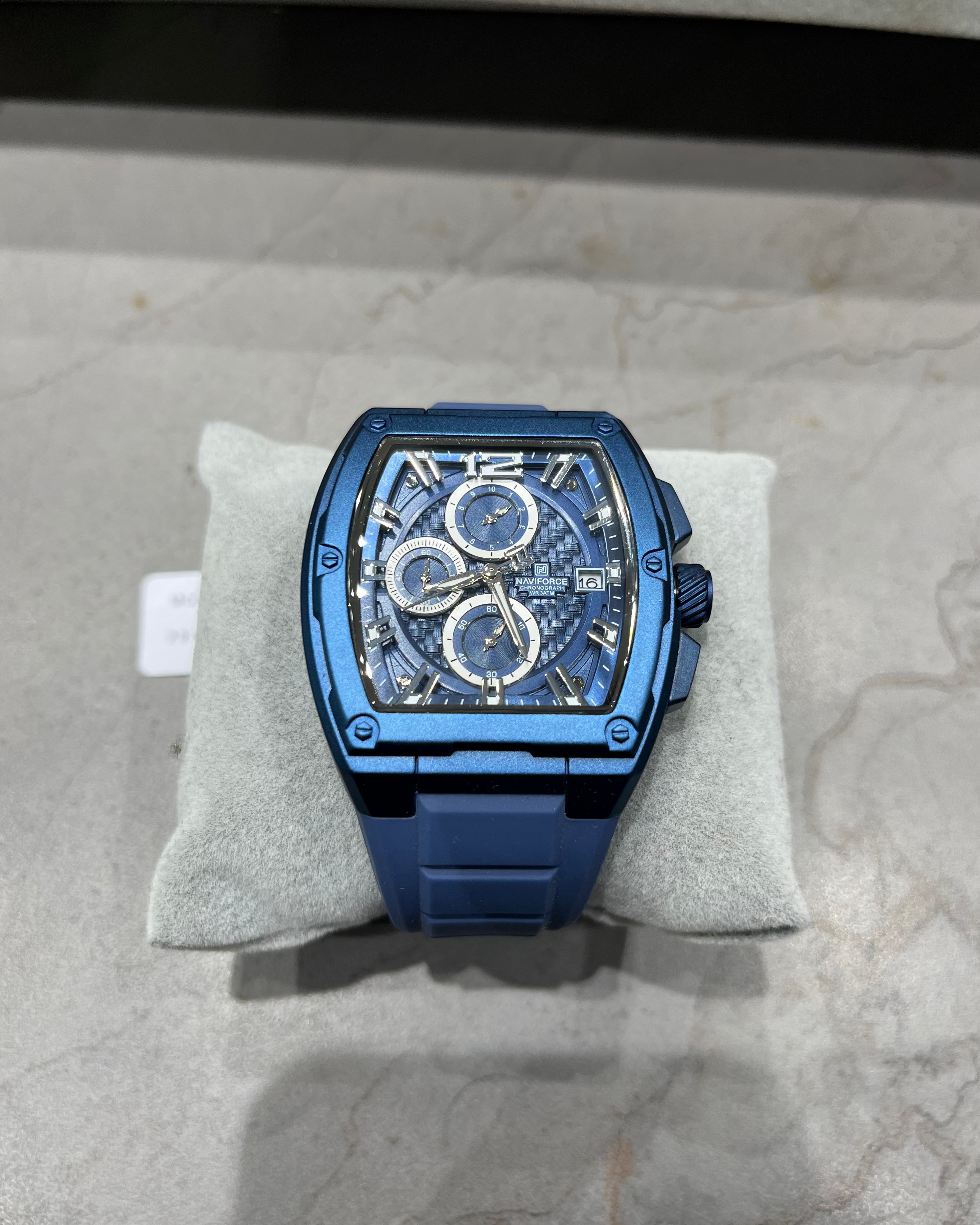 Blue watch on a gray cushion with a neutral background
