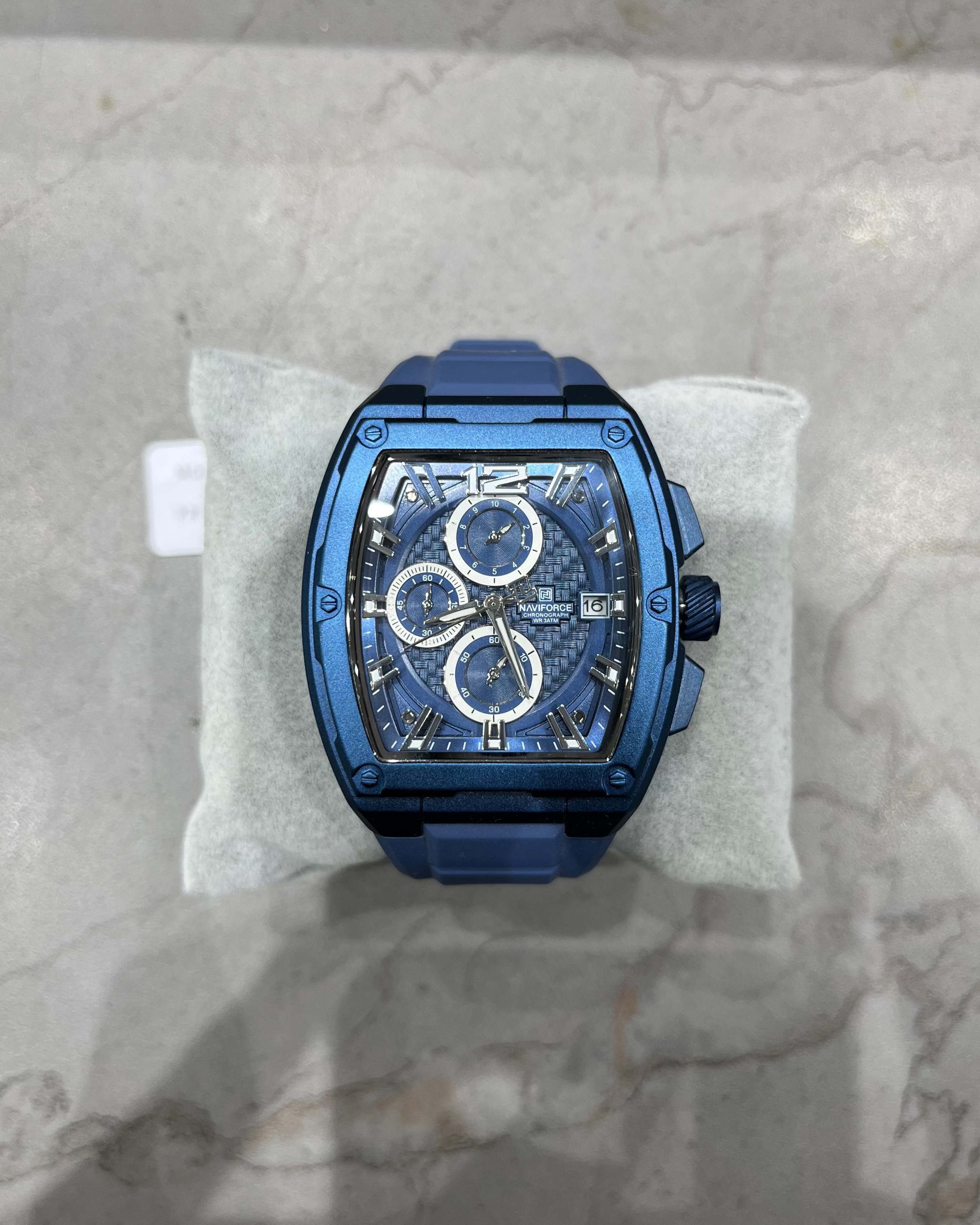 Blue watch on a white cushion with a marble background