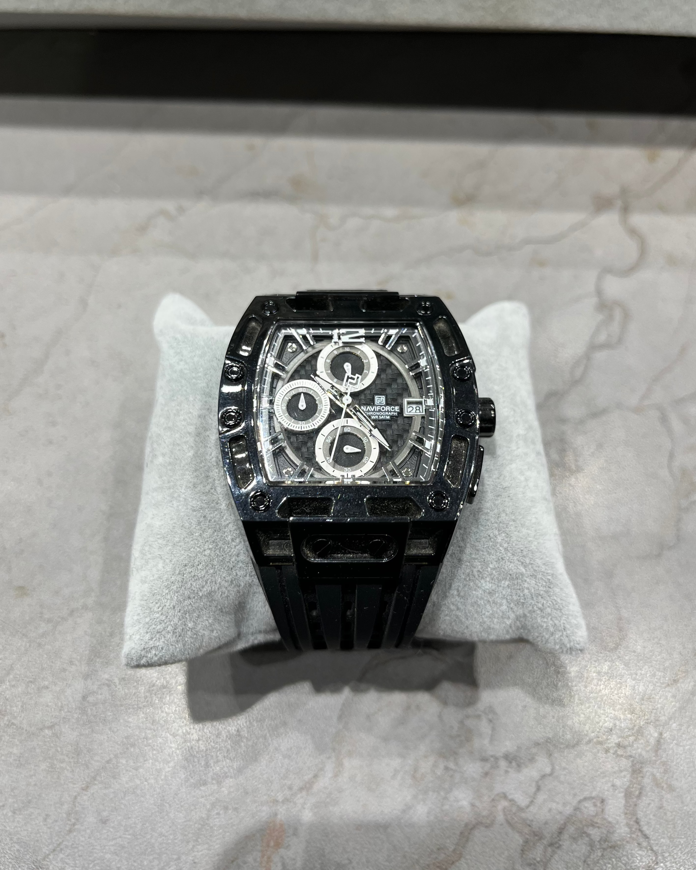Black watch on a white cushion with a gray background