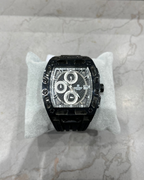 Black luxury watch on a white cushion with a marble background
