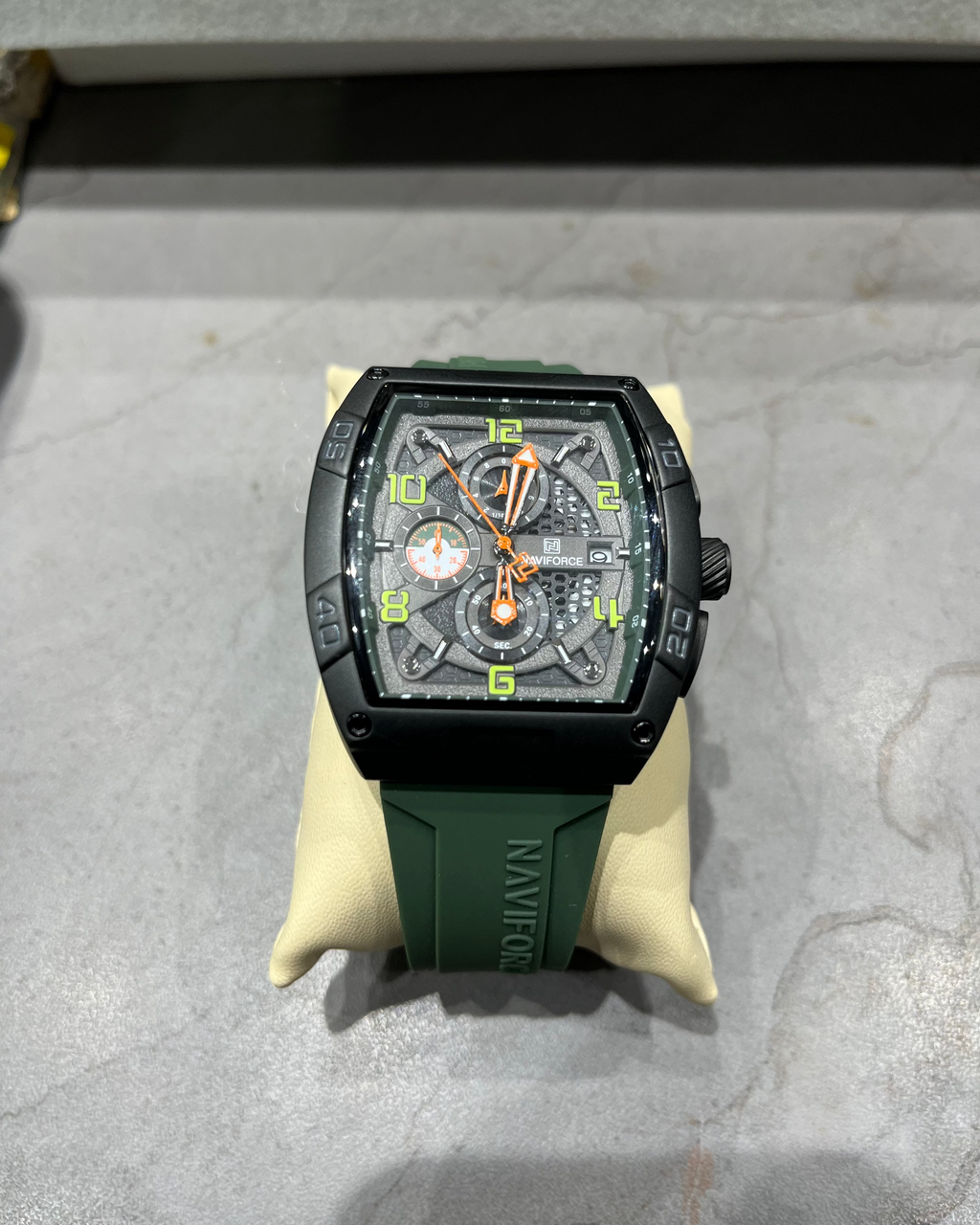 Wristwatch with green strap on a gray surface