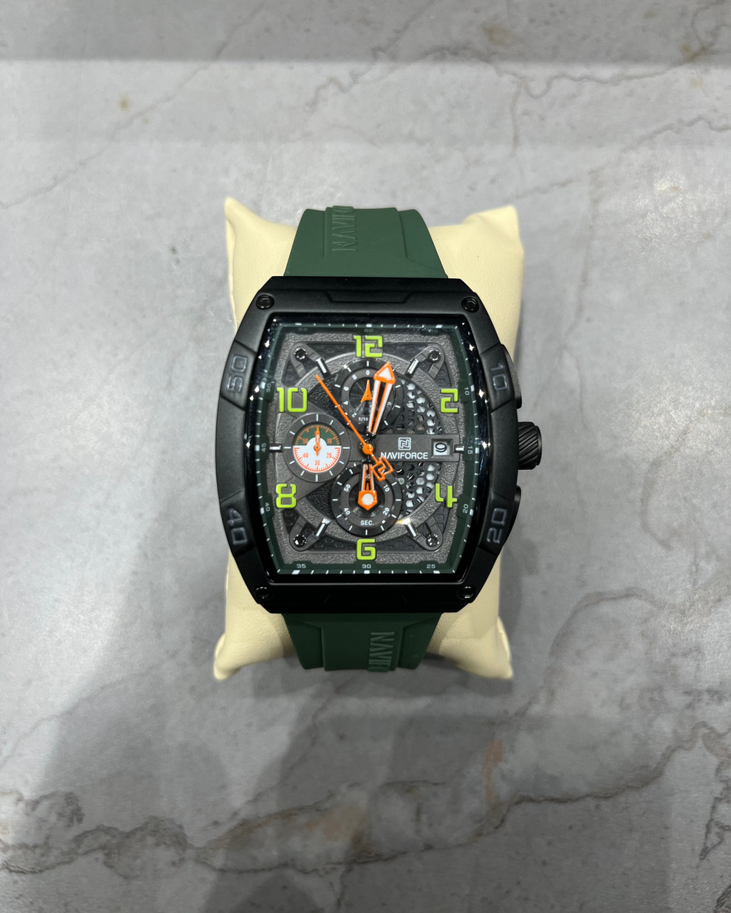 Luxury watch with green strap and black case on a marble surface